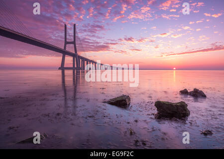Vasco da Gama Bridge across River Tagus silhouetted against pink morning sky, Lisbon, Portugal Stock Photo