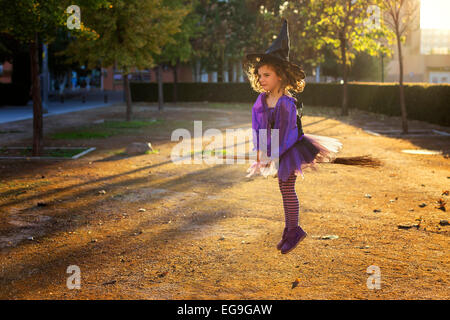 Girl dressed as a witch flying on a broomstick Stock Photo