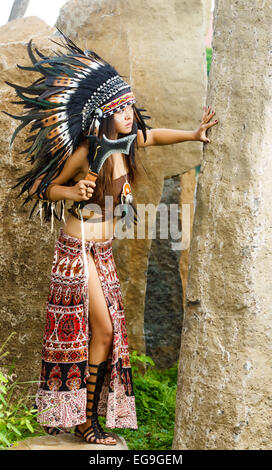 Native american, Indians in traditional dress, standing with ax in the red skirt. Stock Photo