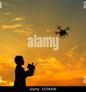 Silhouette of boy Flying a drone at sunset Stock Photo