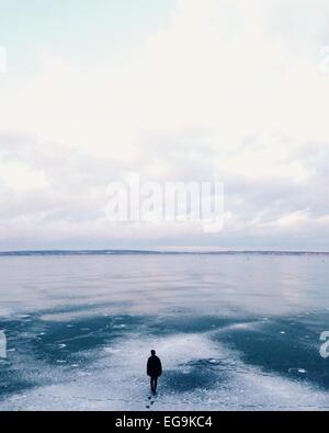 Man hauls his ice fishing shack on a sled across a frozen lake