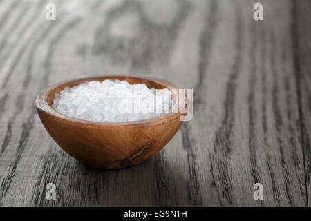 sea salt in wooden bowl for cooking or spa, on dark table Stock Photo