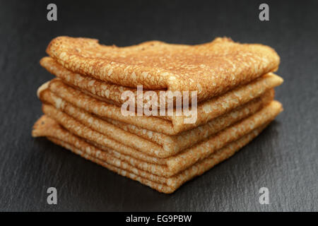 thin crepes or blinis folded in triangles on slate board Stock Photo
