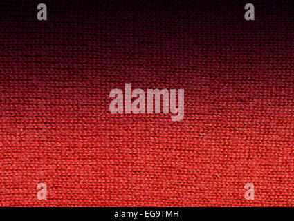 Red wool knitwork fade to black. Red wool knitwork full frame for warming backdrop or background. Stock Photo