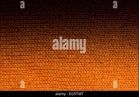 Orange wool knitwork fade to black. Orange wool knitwork full frame for warming backdrop or background. Stock Photo