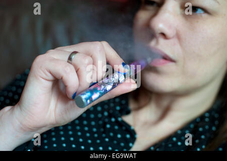 a woman relaxing smoking an e cigarette and blowing out vapour Stock Photo