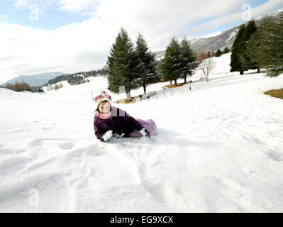 little girl with wool beret playing on snow in the winter in the mountains Stock Photo