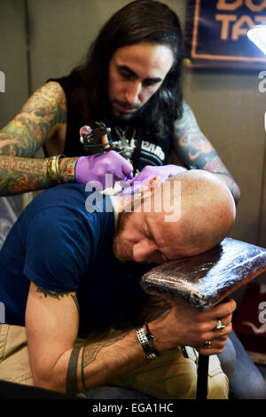 Brighton, UK. 20th February, 2015. A man has a tattoo put on his neck at the 8th Brighton Tattoo Convention Stock Photo