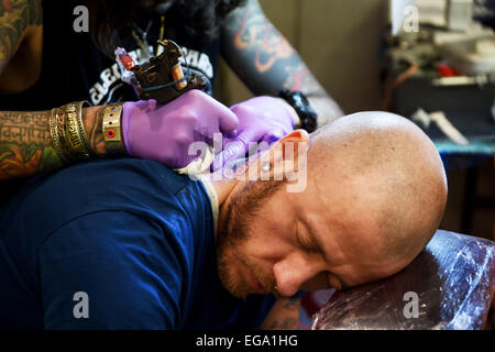 Brighton, UK. 20th February, 2015. A man has a tattoo put on his neck at the 8th Brighton Tattoo Convention Stock Photo