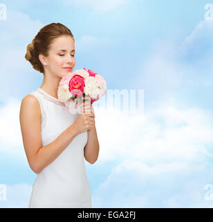 smiling woman in white dress with bouquet of roses Stock Photo