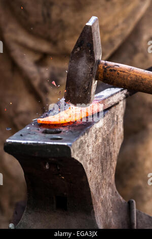 Blacksmith working on metal on anvil at forge detail shot Stock Photo