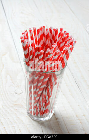 Closeup of a glass filled with red and white striped drinking straws on the rustic white wood table. Vertical format with copy Stock Photo