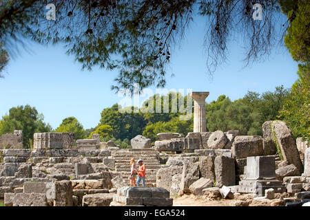 Couple in the ruins of the Temple of Zeus, with its single reconstructed column at Ancient Olympia, The Peloponnese, Greece Stock Photo