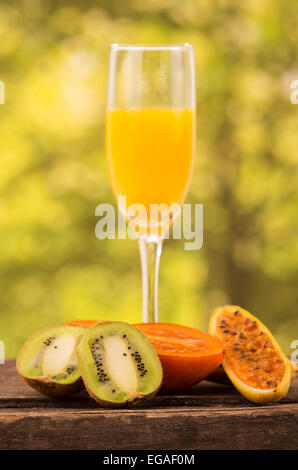 glass of juice with  kiwi, tree tomato and banana passionfruit slices on a wooden table Stock Photo