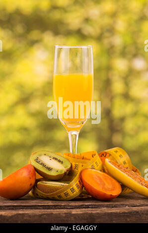 glass of juice with  kiwi, tree tomato and banana passionfruit slices on a wooden table Stock Photo