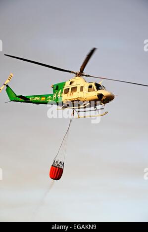 Bell 412 registration EC-IPM carrying water for fire fighting, Cabopino Golf, Costa del Sol, Malaga Province, Andalucia, Spain, Stock Photo