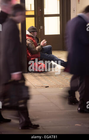 A man watching his mobile, sitting in a doorway on Regent's Street, central London during rush hour. Stock Photo