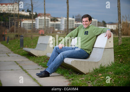 Young man sitting on a cement bench at a park Stock Photo