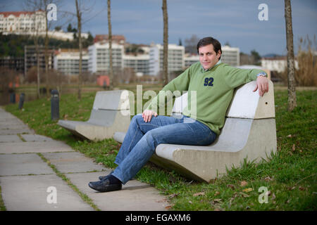 Young man sitting on a cement bench at a park Stock Photo