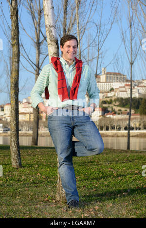 Young man leaning on a tree in a park Stock Photo