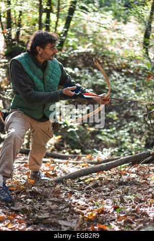 longbow man practicing archery in a forest Stock Photo