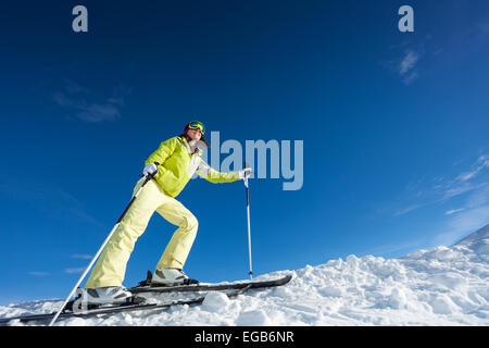 Young woman in mask holding ski poles and skiing Stock Photo