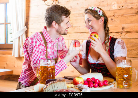 Couple having dinner at mountain hut in alps drinking beer and eating cold cuts Stock Photo