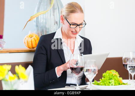 Business woman with tablet in restaurant having lunch in restaurant Stock Photo