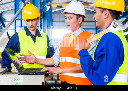 Team of workers and engineer  in Factory at production training with laptop Stock Photo