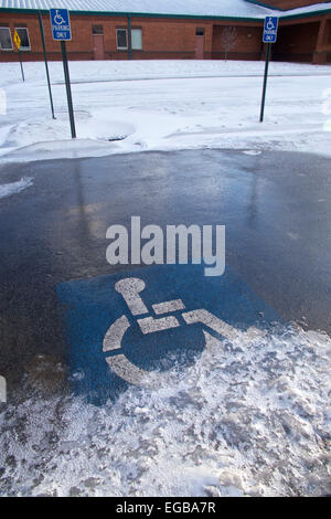 Handicap only parking symbol on snowy parking space at elementary school. Stock Photo