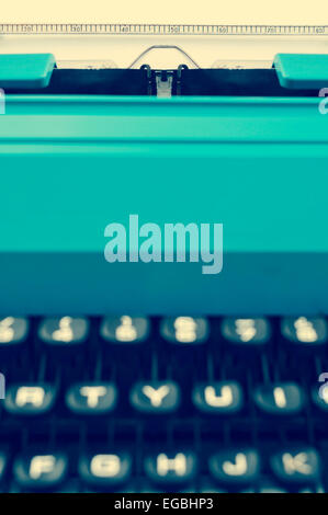 closeup of a retro blue typewriter with a blank page in its roller, with a filter effect Stock Photo