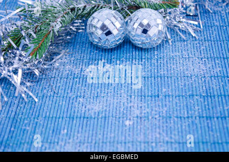 two shiny disco balls on a fir branch covered with snow on white background Stock Photo