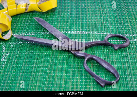 Old scissors and a tape measure on green background Stock Photo
