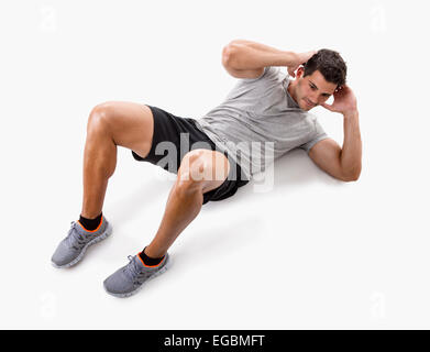 Athletic man doing abdominals, isolated over a white background