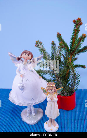 Two angel figurines and a fir tree on blue Stock Photo