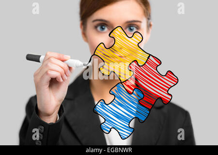 Businesswoman drawing a puzzle on a glass board Stock Photo