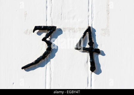 England, Sandwich. Front door, street Number 34. White wooden panelled door with black metal numbers on. Stock Photo