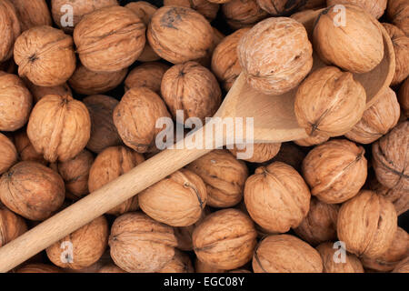 Wooden spoon with three walnuts on a background of a walnut Stock Photo
