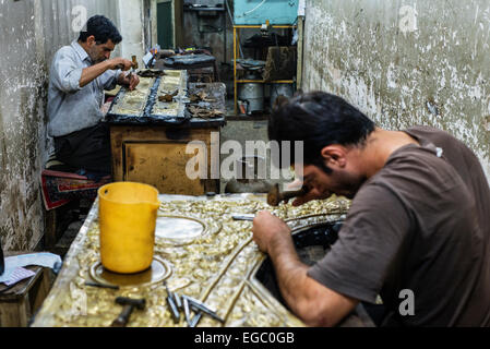Artists emboss ghalamzani cooper pieces, ghalamzani means art of embossing patterns on different metals such as copper, silver, gold, and brass, Esfahan, Iran Stock Photo