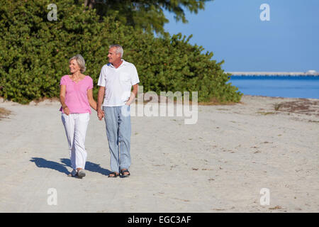 Senior man and woman couple holding hands walking on a deserted beach Stock Photo
