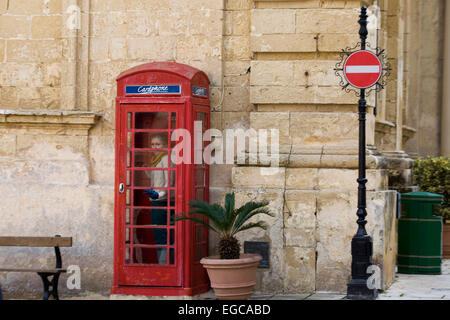 Tourist in a Red Public Telephone Box in Malta Stock Photo