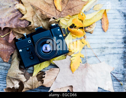 Retro camera amoung colorful autumn leaves on a wooden background with copy space Stock Photo
