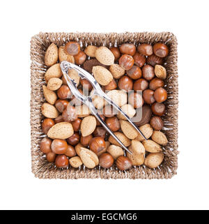Mixed nuts in a woven basket with nut cracker, isolated on white Stock Photo
