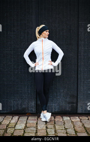 Full length shot of sporty young woman relaxing after running exercise. Female athlete resting after jogging in the city. Stock Photo