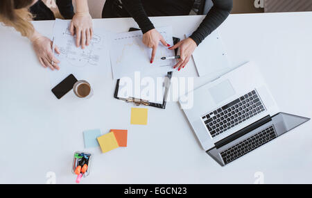Top view of hands of two business woman analyzing financial data. Coworkers working on chart at desk in office. Stock Photo