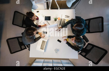 Overhead view of diverse team analyzing data while sitting at office. Multiracial business people in a meeting working. Stock Photo