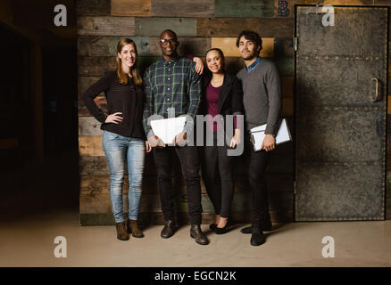 Portrait of successful business team standing together against wooden wall. Full length image of a group of diverse colleagues Stock Photo