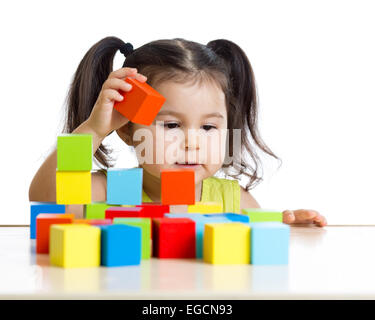 toddler girl builds a tower with colorful blocks Stock Photo