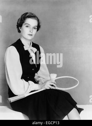 1940s WOMAN SITTING BENCH HOLDING BADMINTON RACKET & SHUTTLECOCK WEARING A DARK VEST BLOUSE LOOKING AT CAMERA Stock Photo