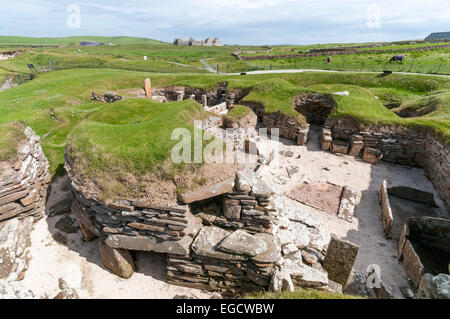 House 5 at Skara Brae Neolithic Village on Mainland Orkney with Skaill House in the background. Stock Photo